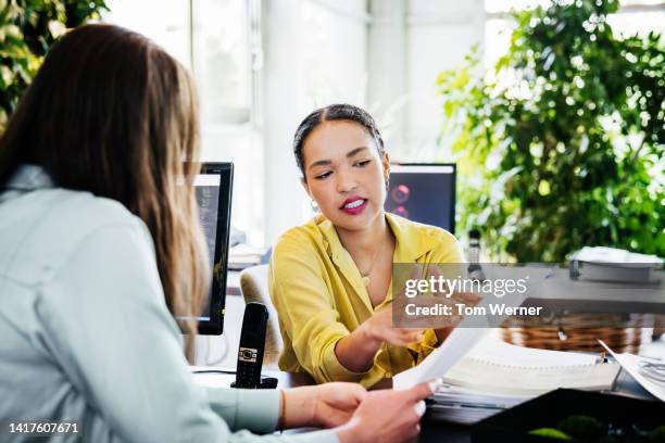 woman looking at paperwork with office colleague - boss photos et images de collection