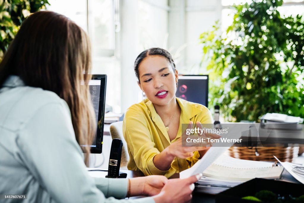 Woman Looking At Paperwork With Office Colleague