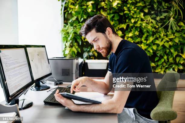 office employee concentrating while working at his desk - arabic keyboard fotografías e imágenes de stock