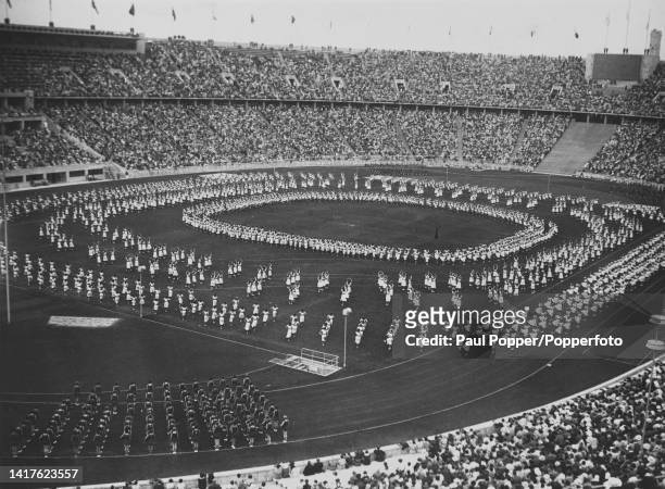 Spectators seated in the stadium to watch dancers and gymnasts take part in the opening ceremony of the 1936 Summer Olympics inside the...