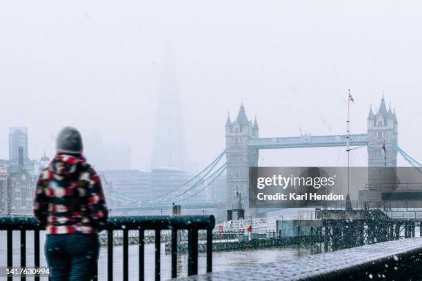 an unrecognizable woman looks at the london skyline in the snow - one embankment stock pictures, royalty-free photos & images