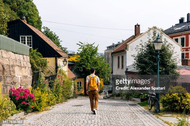 rear view of a man with backpack walking in oslo historical old town, norway - oslo stockfoto's en -beelden