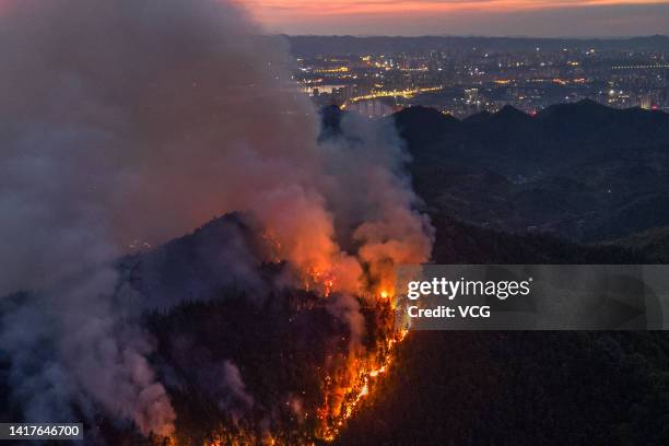 Smoke and flames rise from a mountain during a wildfire in Banan district on August 23, 2022 in Chongqing, China. The wildfire that broke out last...