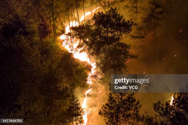 Smoke and flames rise from a mountain during a wildfire in Banan district on August 23, 2022 in Chongqing, China. The wildfire that broke out last...