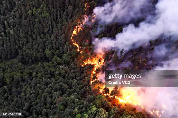 Smoke and flames rise from a mountain during a wildfire in Banan district on August 23, 2022 in Chongqing, China. The wildfire that broke out last...