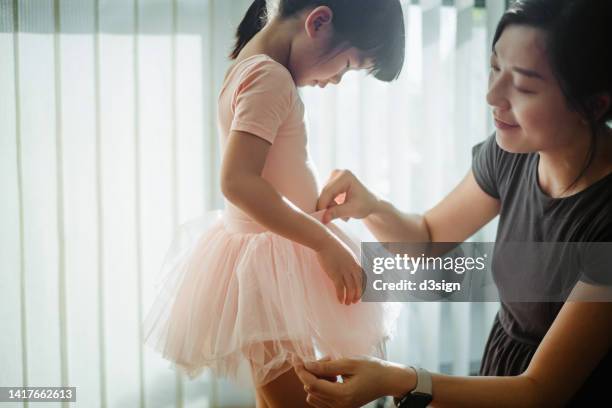 loving young asian mother preparing daughter for ballet class, getting dressed her daughter in pink ballerina costume and tutu. hobbies and interests. family lifestyle. mother and daughter moment. love, care and bonding concept - menina fantasia bonita imagens e fotografias de stock