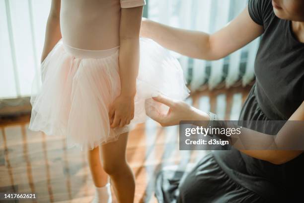 cropped shot of loving young asian mother preparing daughter for ballet class, getting dressed her daughter in pink ballerina costume and tutu. hobbies and interests. family lifestyle. mother and daughter moment. love, care and bonding concept - help getting dressed stock pictures, royalty-free photos & images
