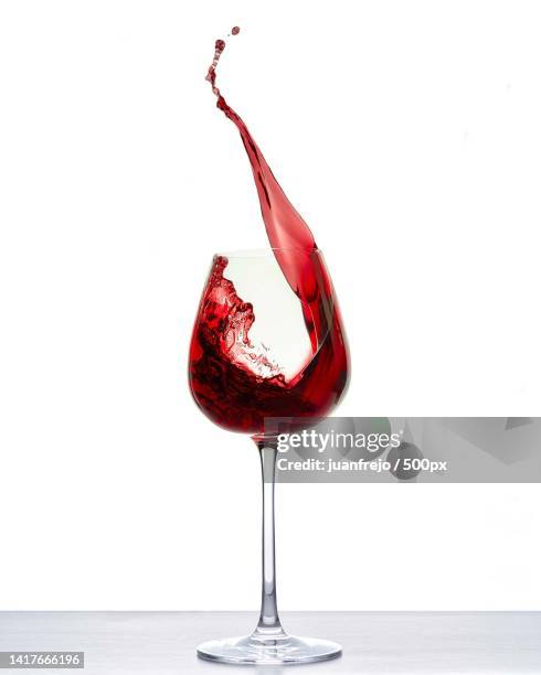 close-up of red wine splashing on table against white background - verre vin rouge photos et images de collection