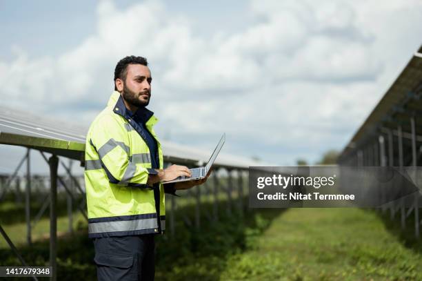 renewable energy resource field assessment. side view of male solar energy engineers use a laptop computer in a solar panels module to assessment and analyzing solar resource measurements for next project. - remote location fotografías e imágenes de stock