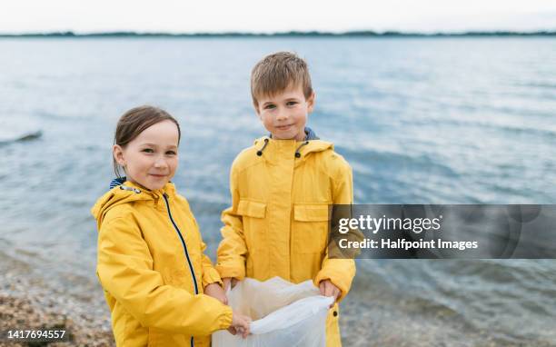 happy friends tidying trashes from the river. looking at camera. - doing a favor stockfoto's en -beelden