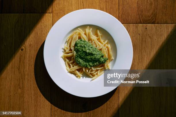 still life pasta with pesto sauce in bowl on sunny table - pesto stock-fotos und bilder