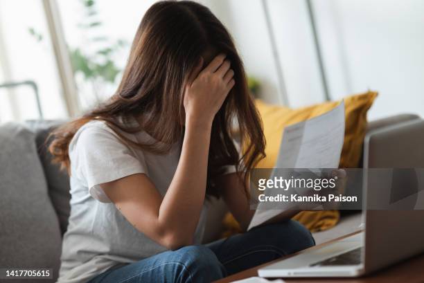 joven asiática preocupada mirando el documento financiero, sintiéndose estresada por la factura alta y la deuda vencida. - depresión económica fotografías e imágenes de stock