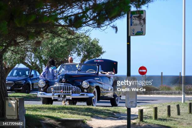 a 1948 buick super eight convertible in a parking lot on the beach of sables-d'or-les-pins, brittany, france - summer super 8 stockfoto's en -beelden