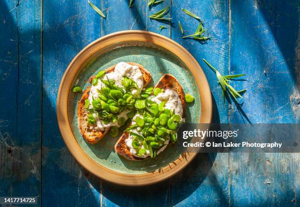 littlebourne, kent, england, uk. 16 july 2022. broad (fava) beans with feta cheese on sourdough bruschetta - dragon stockfoto's en -beelden