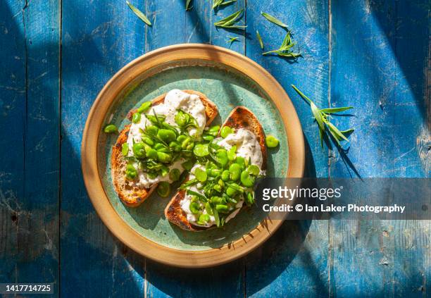 littlebourne, kent, england, uk. 16 july 2022. broad (fava) beans with feta cheese on sourdough bruschetta - fava bean stock pictures, royalty-free photos & images