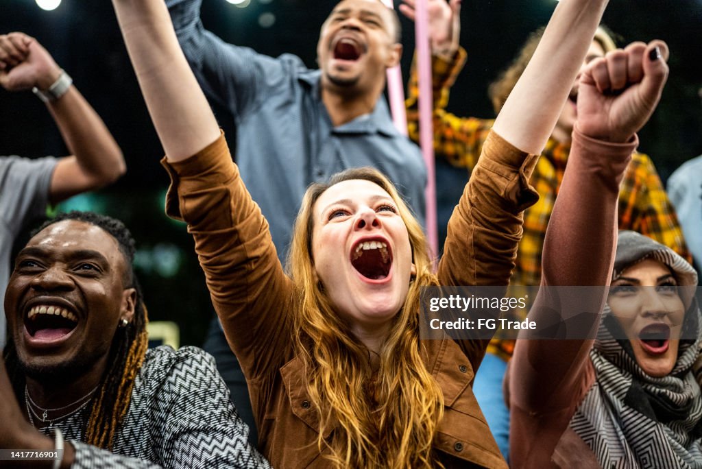 Amici che guardano una partita sportiva e festeggiano all'aperto