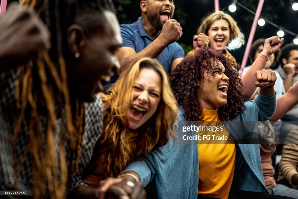 Friends watching a sports game and celebrating outdoors