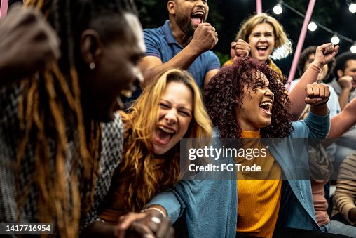 Friends watching a sports game and celebrating outdoors Friends watching a sports game and celebrating outdoors