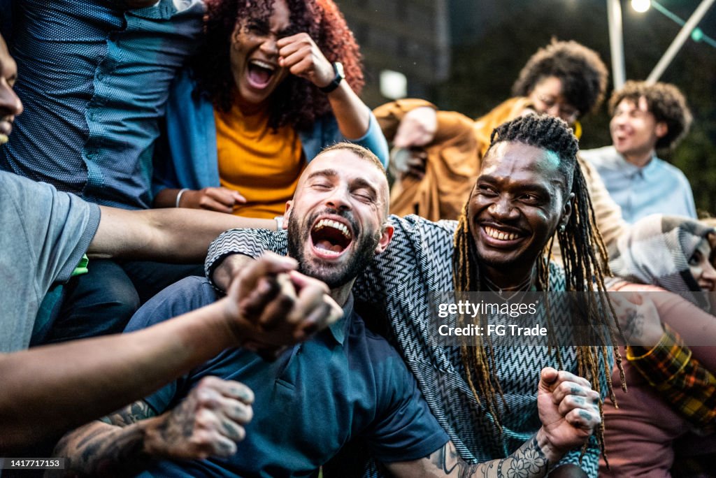 Friends watching a sports game and celebrating outdoors