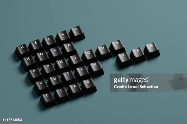 digitally generated image of greeting words written in various languages typed with black keyboard keys on blue background. - teclado pequeño fotografías e imágenes de stock