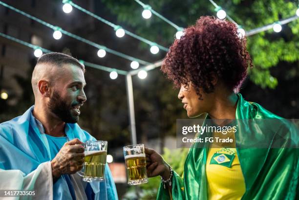 sports fan friends talking and drinking a beer outdoors - friend enemy stock pictures, royalty-free photos & images