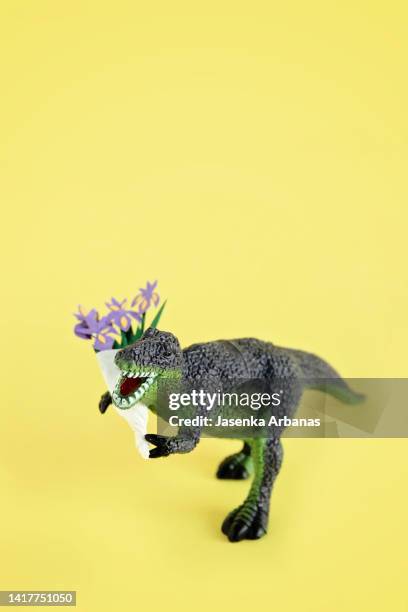 toy dinosaur with a bouquet of flowers - funny dinosaur stock pictures, royalty-free photos & images