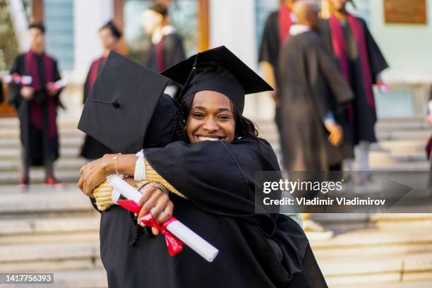 young student is embracing each other after the graduating ceremony - black woman graduation stock pictures, royalty-free photos & images