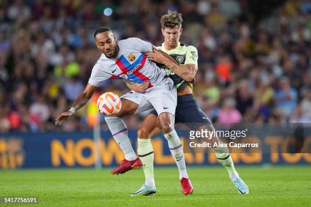 Pierre-Emerick Aubameyang of FC Barcelona is challenged by John Stones of Manchester City during the friendly match between FC Barcelona and...