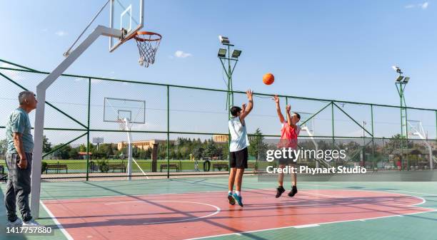 ティーンエイジャーの男の子はコーチと一緒にバスケットボールを練習しています - トレーニングドリル ストックフォトと画像