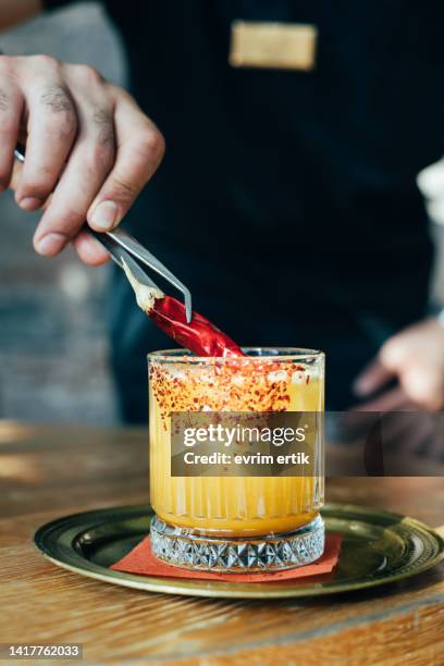 bartender putting chili pepper on passion margarita coctail - barman tequila stockfoto's en -beelden