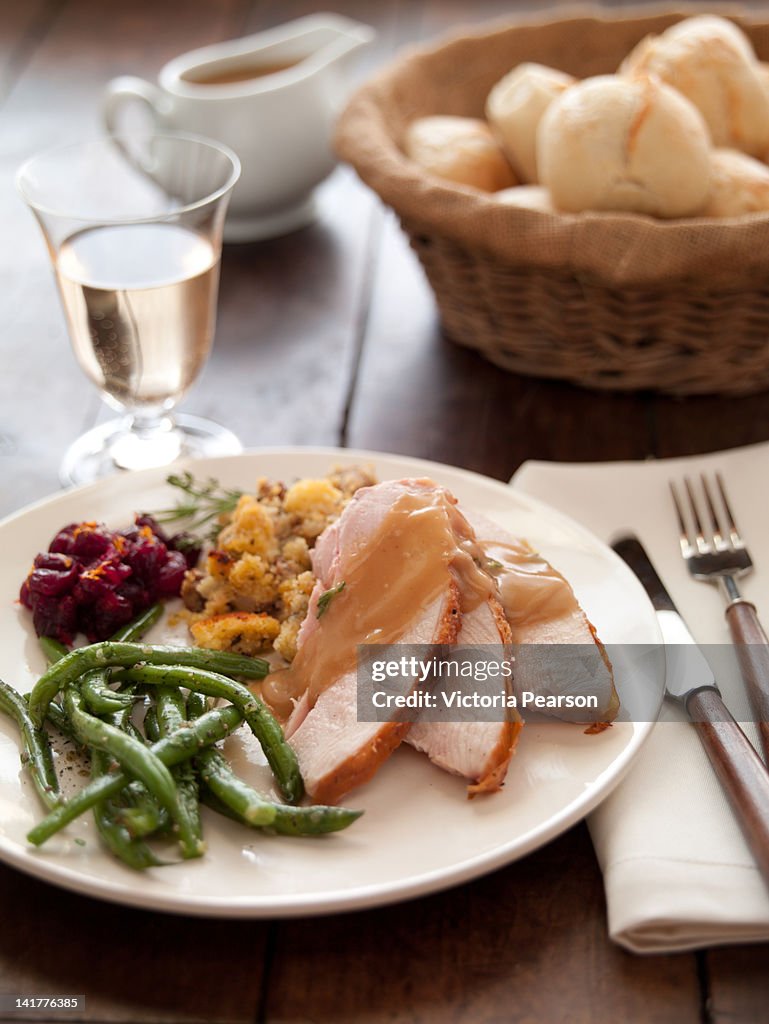 Thanksgiving meal on plate; rolls & white wine.