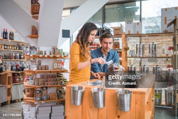 caucasian couple shopping organic goods in a sustainable store - filling jar stock pictures, royalty-free photos & images
