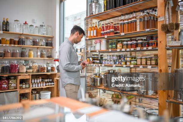 asian mid adult male shopping in a zero waste shop - mason jar stock pictures, royalty-free photos & images