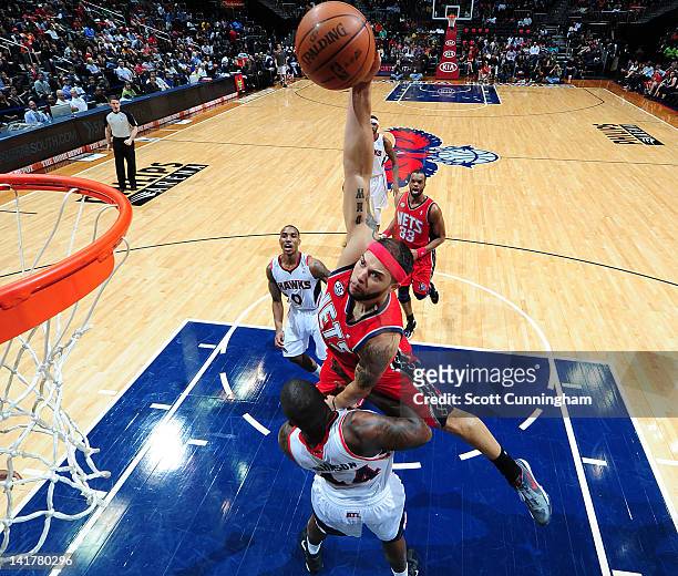 Deron Williams of the New Jersey Nets dunks the ball over Ivan Johnson of the Atlanta Hawks on March 23, 2012 at Philips Arena in Atlanta, Georgia....