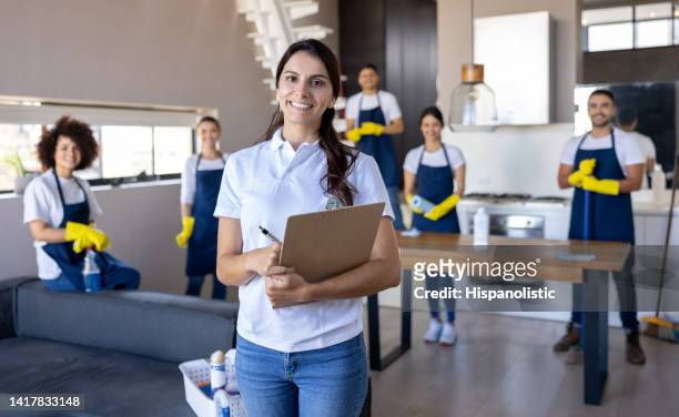mujer de negocios al frente de un grupo de limpiadores profesionales - criado fotografías e imágenes de stock