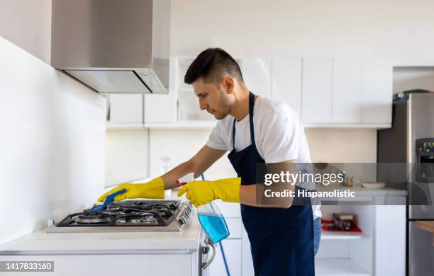 professional cleaner cleaning the stove at an apartment - janitorial services stockfoto's en -beelden