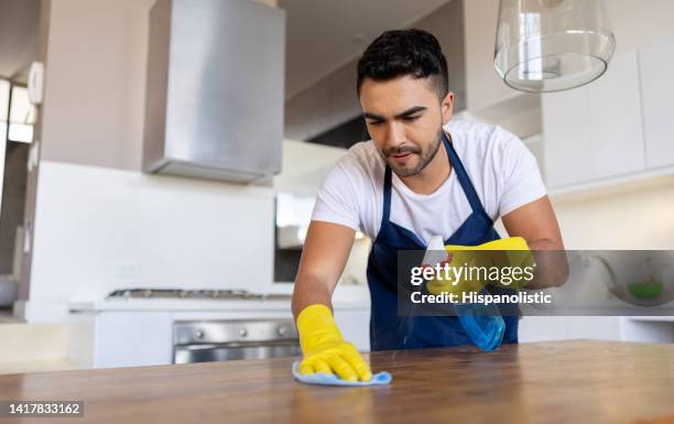 professional cleaner cleaning a table while working at a house - cleaner man uniform stock pictures, royalty-free photos & images