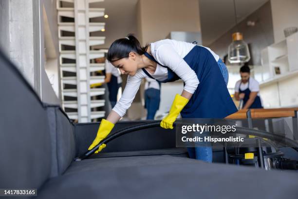 professional cleaner vacuuming the couch while working at an apartment - cleaning crew stock pictures, royalty-free photos & images