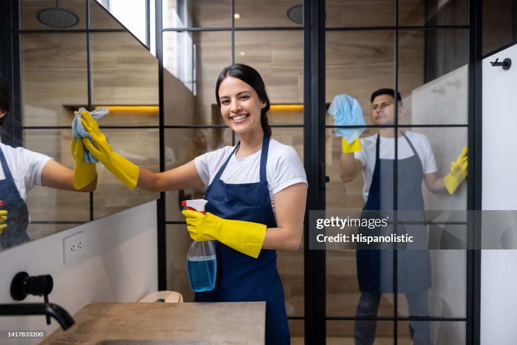 Des nettoyeurs professionnels heureux nettoyant une salle de bain dans un appartement