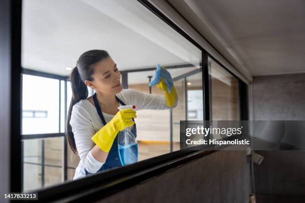 professional cleaner cleaning a glass window at an apartment - commercial cleaning stock pictures, royalty-free photos & images