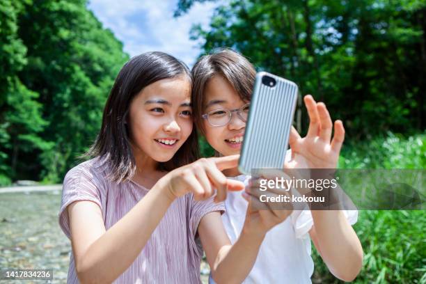 two teenagers take selfies happily in the nature - japan 12 years girl stock pictures, royalty-free photos & images