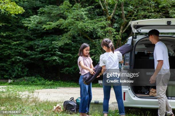 a father and his two daughters prepare to build a tent at a campsite. - car camping luggage stock pictures, royalty-free photos & images