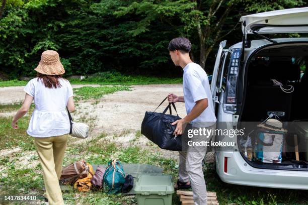 a young couple preparing to build a tent at a campsite. - car camping luggage stock pictures, royalty-free photos & images