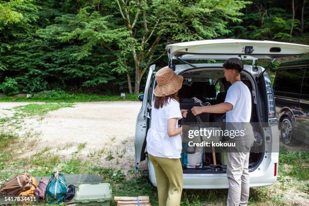 a young couple preparing to build a tent at a campsite. - car camping luggage stock pictures, royalty-free photos & images