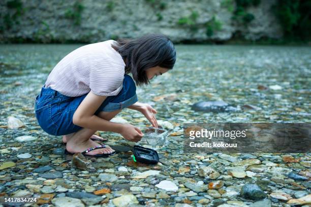 a girl at camping site looks into river water - beautiful barefoot girls stockfoto's en -beelden