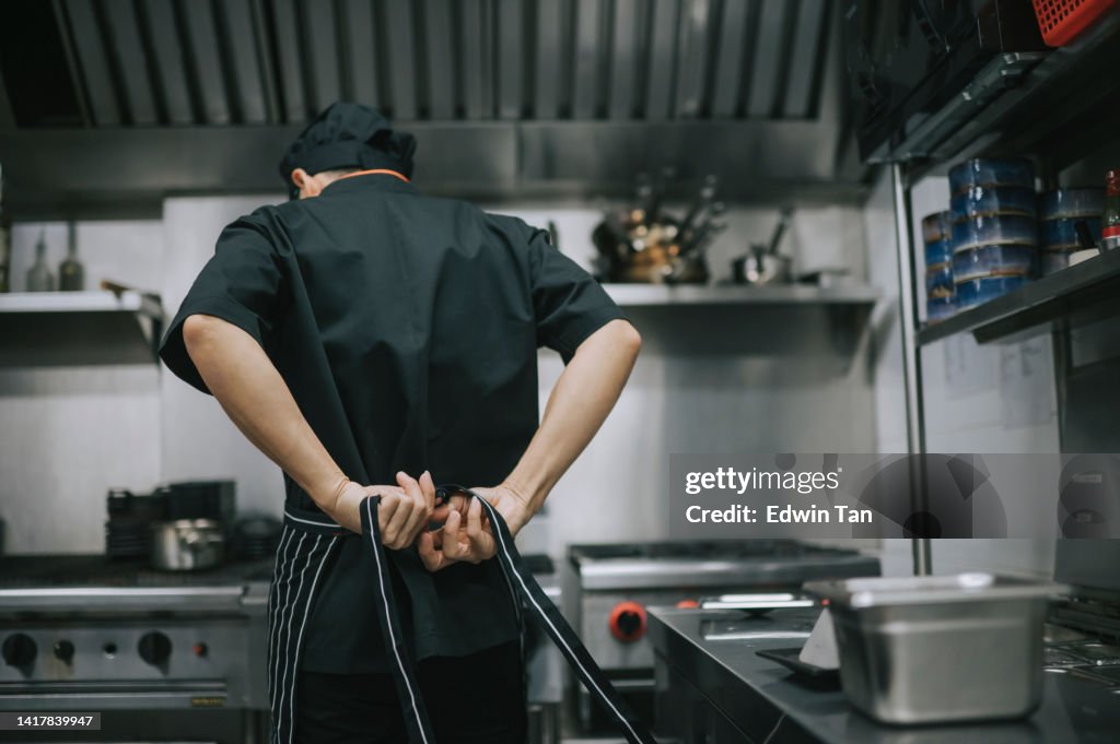 Rear view asian chinese chef tying up apron getting read to work at commercial kitchen