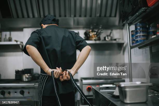 rear view asian chinese chef tying up apron getting read to work at commercial kitchen - hands behind back bildbanksfoton och bilder