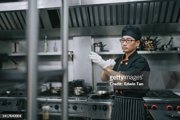 asian chinese chef getting ready put on latex glove in commercial kitchen - apron gloves stock pictures, royalty-free photos & images