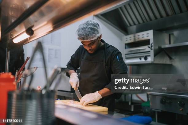 asian indian kitchen crew helper cutting onion preparing food - hotel reopening stock pictures, royalty-free photos & images