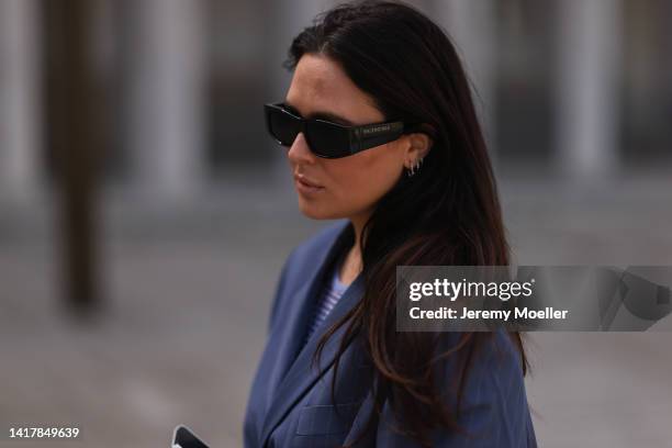 Lou Beyer wearing Balenciaga black statement shades, Bottega Veneta black leather mini Jodie bag, shiny Rotate mini dress, Acne Studios navy blue...